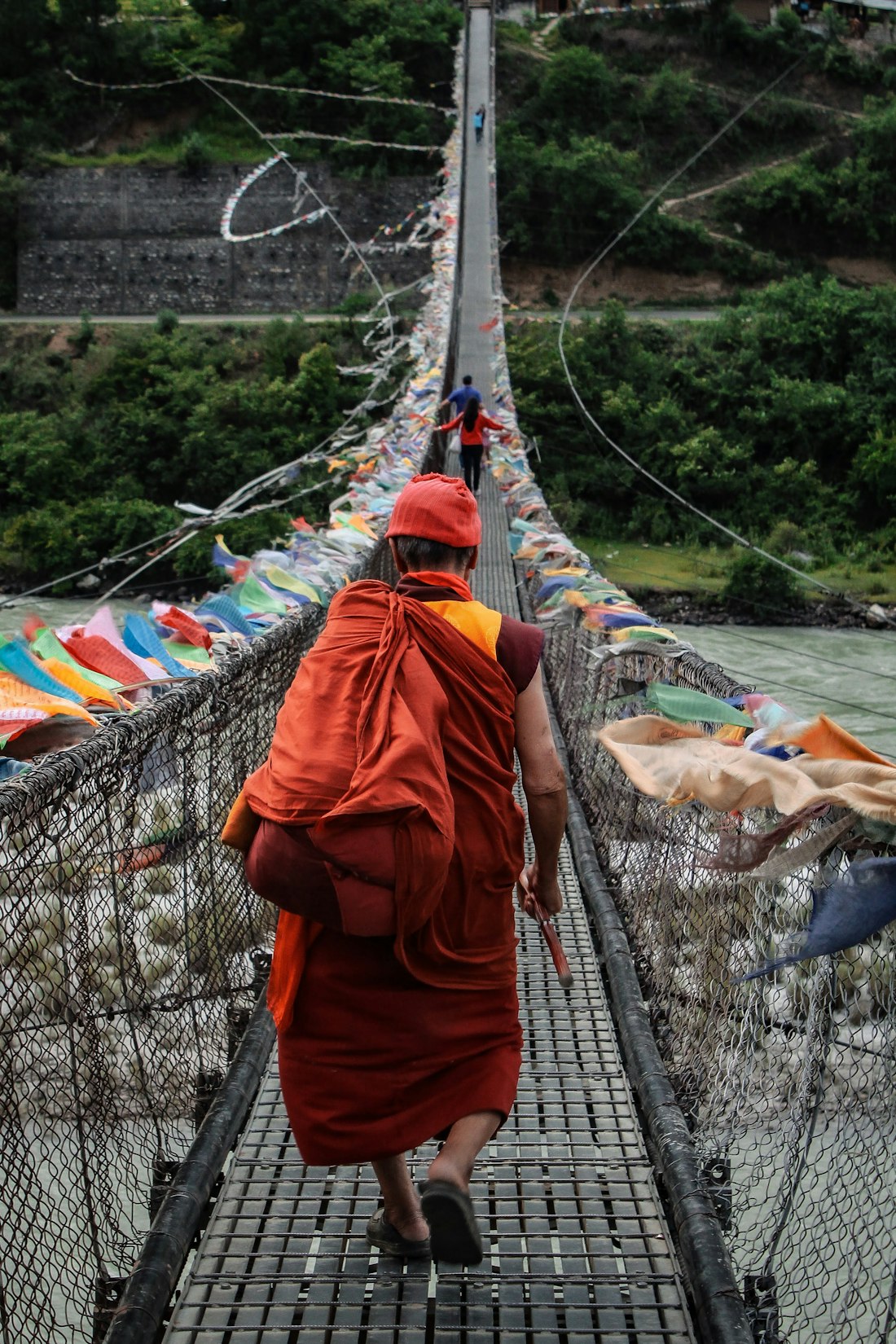 Monk crossing a suspension bridge in Punakha